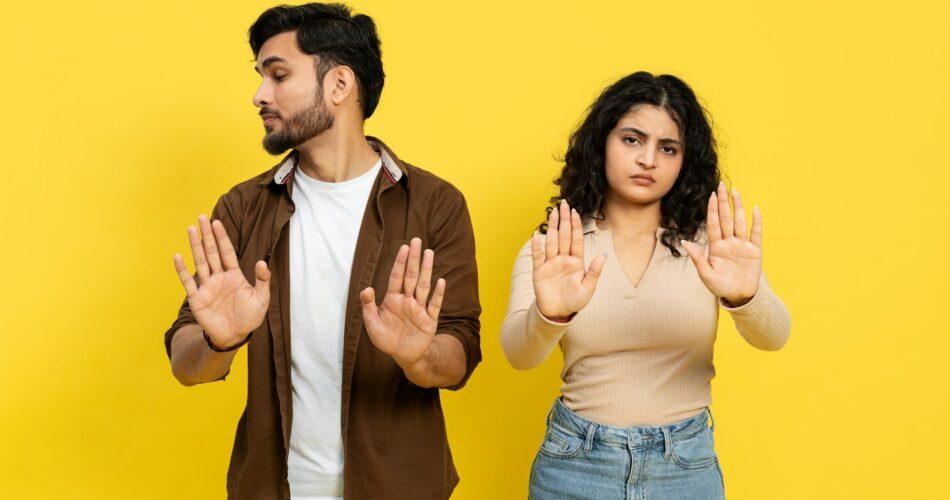 Young Couple Showing Stop Gesture on Yellow Background