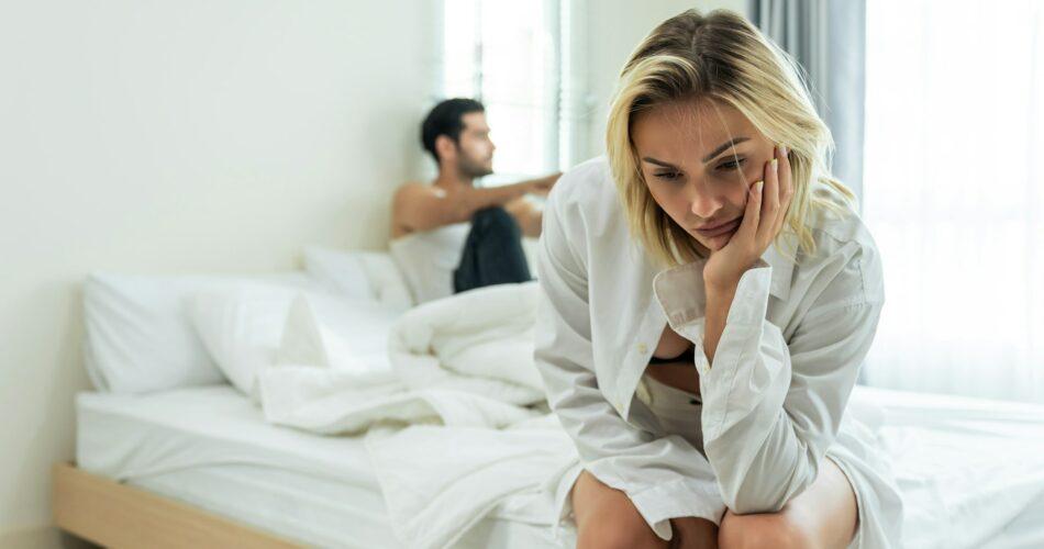 Caucasian young couple sitting on bed with painful after fight argument.