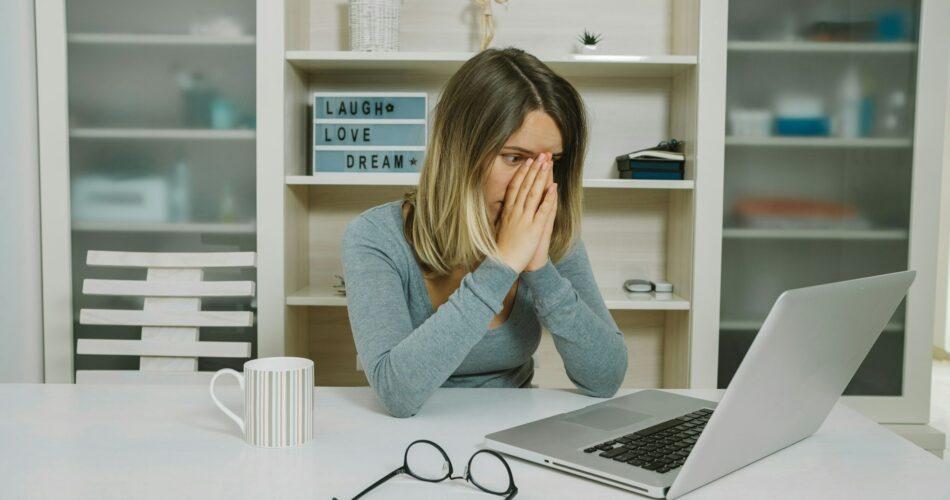 Tired young woman spectacled working on laptop while sitting in office, Everything is bad